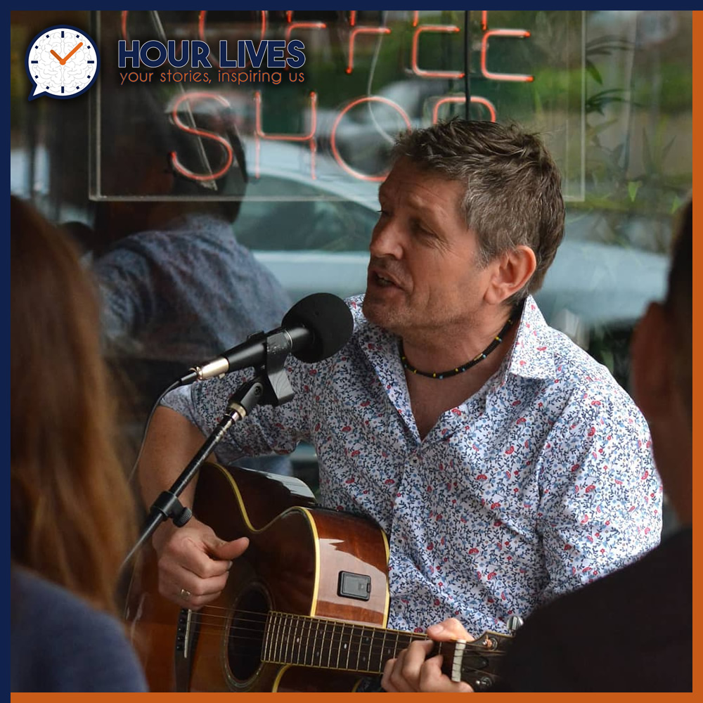 A photo of musician Jim Danby singing and playing his guitar.