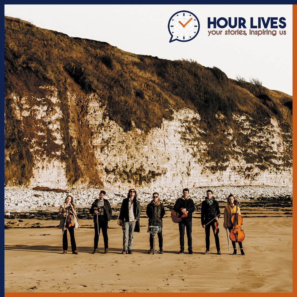 A photo of musicians Pavey Ark stood on a beach in front of a cliff.